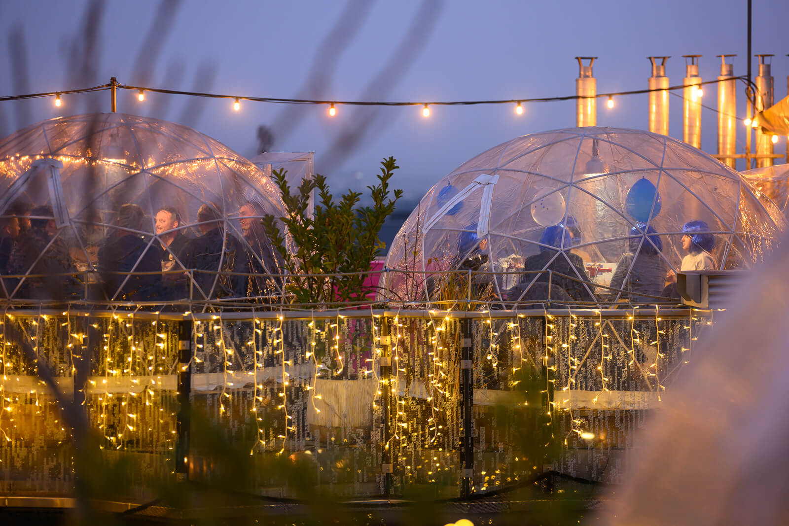 Friends enjoying an evening inside a transparent igloo at Igloo Garden